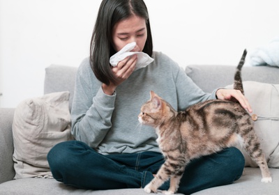 woman sneezing with cat