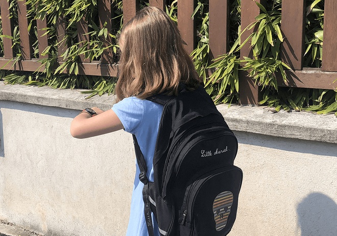 Ein kleines Mädchen mit einer GPS Armbanduhr am Handgelenk auf dem Weg zur Schule