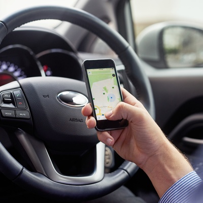 Eine Person in einem Auto, die ihr Smartphone hält, während die Kartenanwendung geöffnet ist