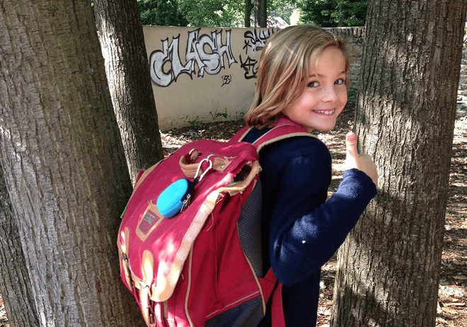 Ein kleines Mädchen mit Schultasche auf dem Rücken und GPS Tracker