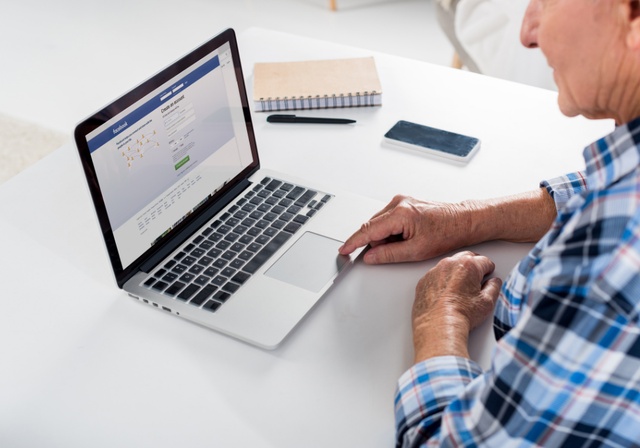 A man going on Facebook on his computer