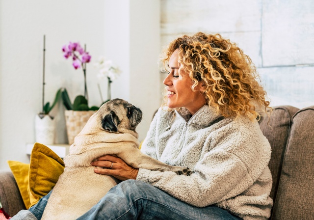 An owner holding his dog in his living room