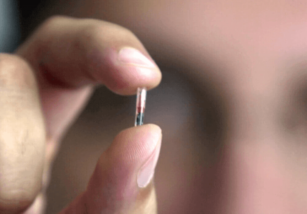 Un homme tient une micro puce entre ses doigts